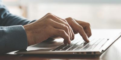Individual typing on their laptop on a desk - advanced writing skills - Email Writing