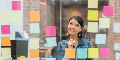 Latin American woman thinking of creative sales ideas at the office to put in a wall chart - agile scrum - managing up