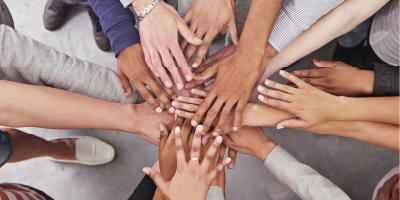 A diverse group of people all putting their hands in the - Leading Partnership Initiatives