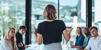 Business woman speaking to other business individuals in a meeting - Accountable Leadership - Executive Core Qualifications Series