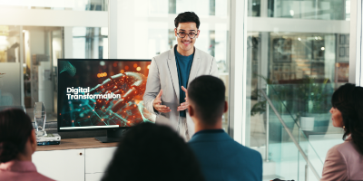 Professional male presenting technical or technology-related information to colleagues in a workplace setting.