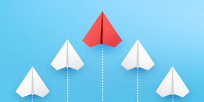 Leadership concept illustrated by a red paper airplane leading a formation of white paper planes, symbolizing guidance and influence.